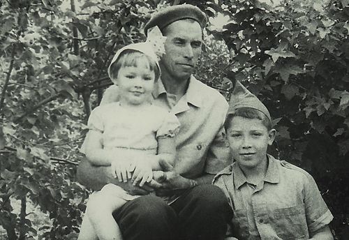 В. А. Волохов с Игорем и Таней на коленках на Барковке летом на фоне сада